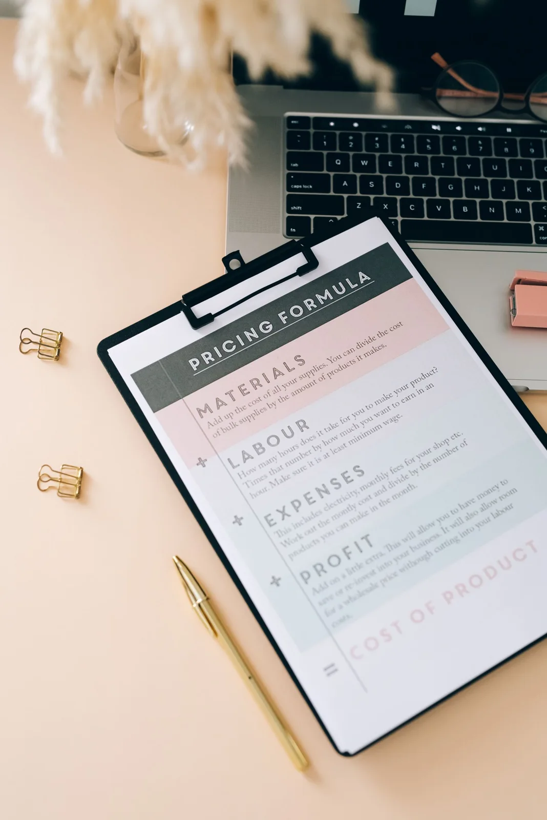 A clipboard with printed pages beside a laptop on a desk