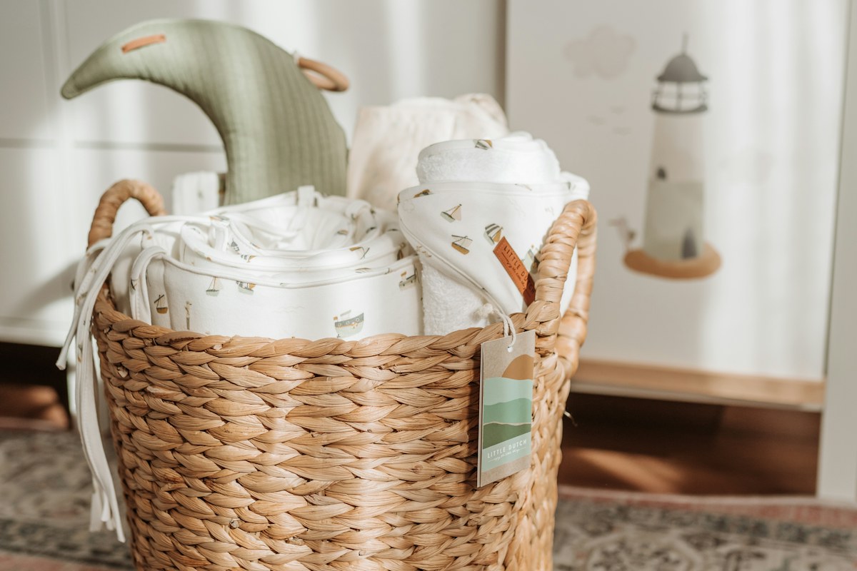 Rolled white textiles in a wicker basket beside an armchair
