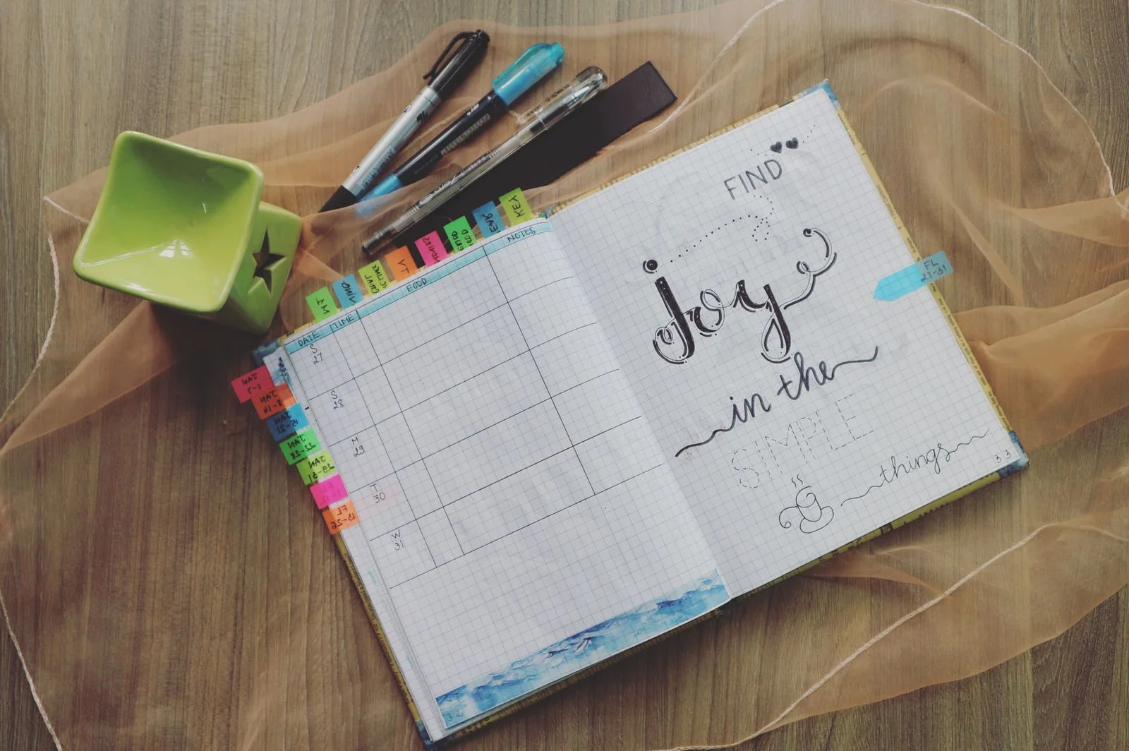 Open planner and pens on a wooden desk