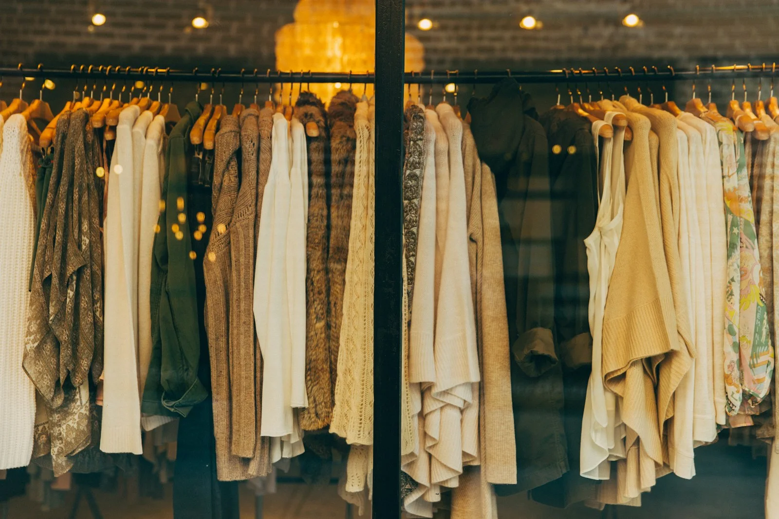 Rows of clothing hang in a warmly lit wardrobe display