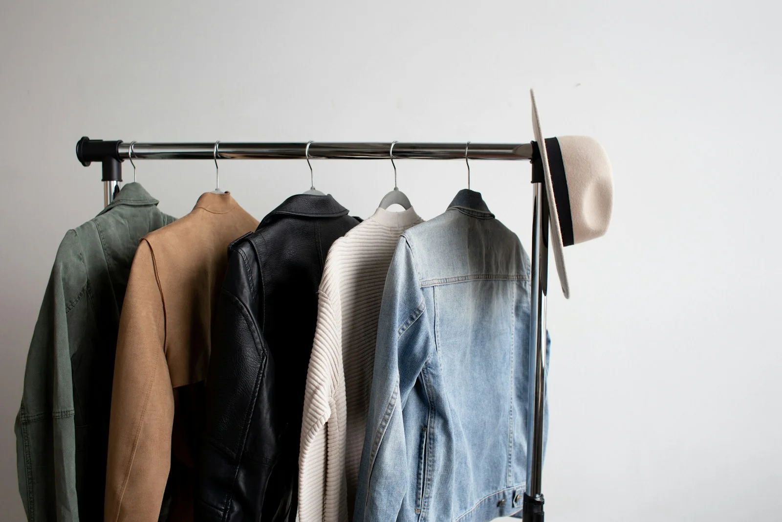 Coats and jackets in muted colours hang on a black rail